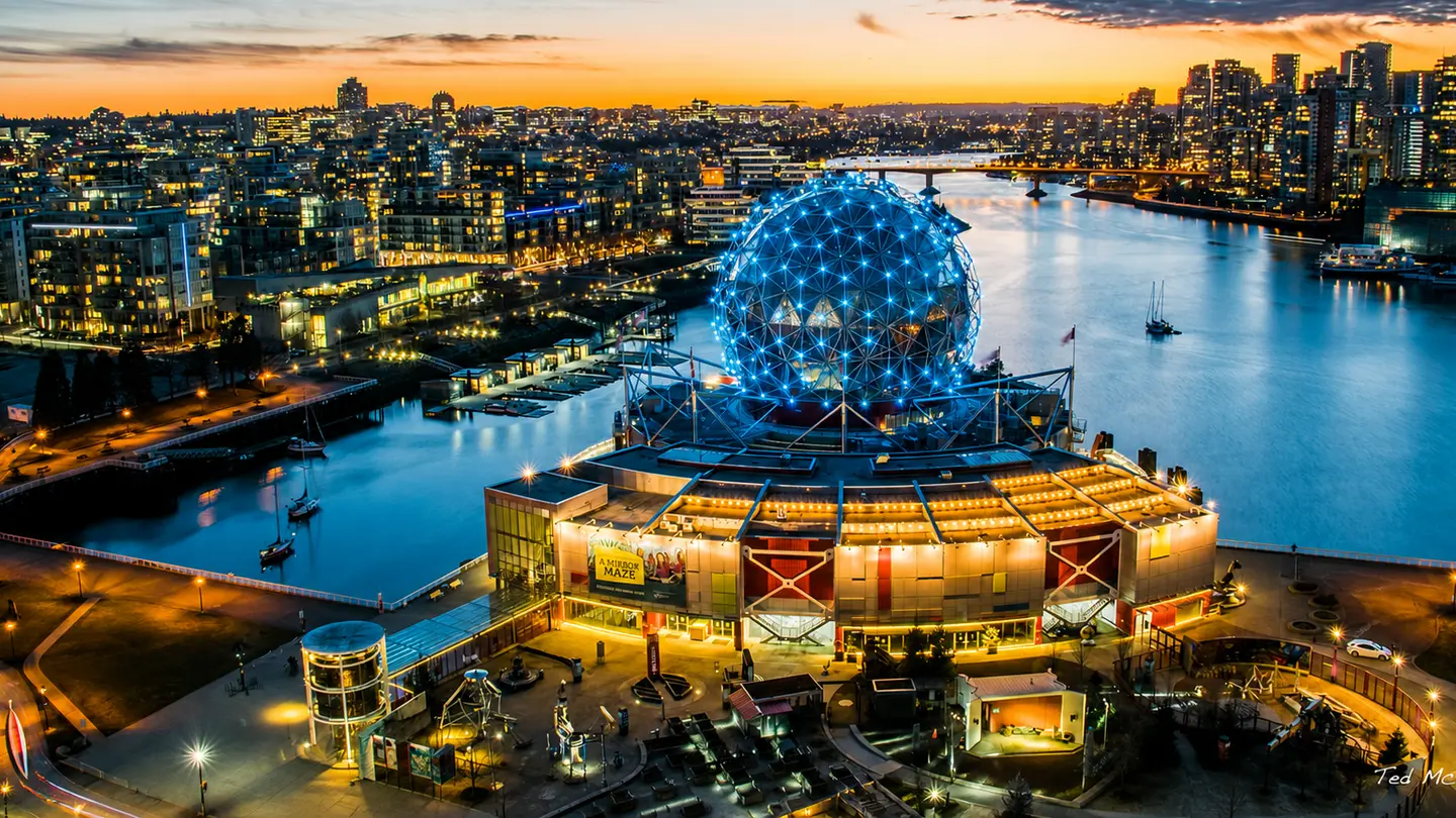Science World lit up beside False Creek at dusk